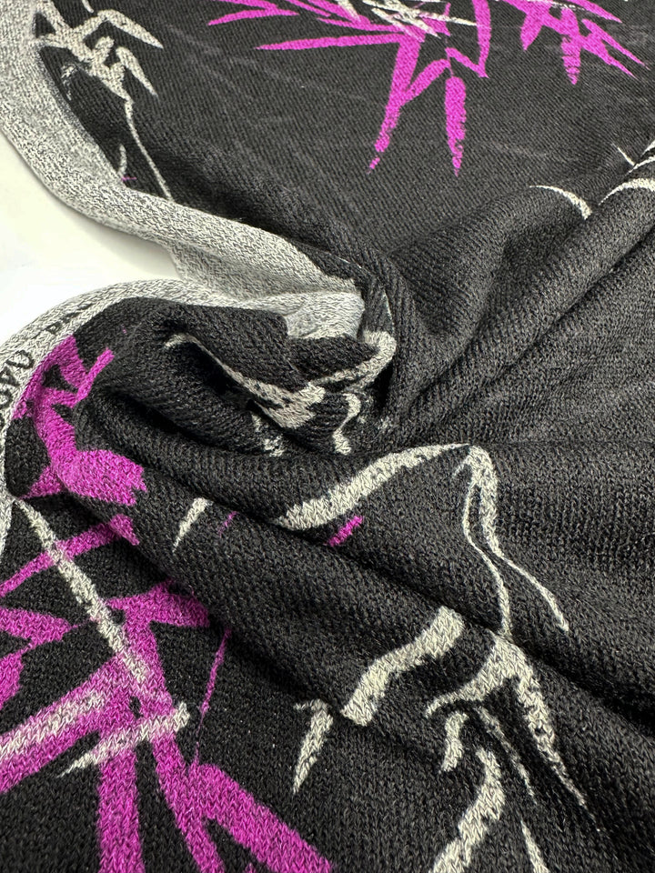 Close-up of Super Cheap Fabrics' Textured Knit - Bamboo, 145cm wide, in black and gray with abstract purple and white floral patterns. The soft woven texture features medium-weight fabric in a slightly gathered design.