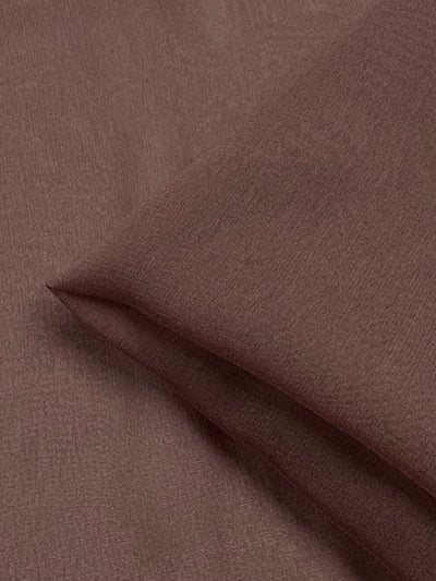 A close-up image of the Silk Georgette - Shroon - 135cm from Super Cheap Fabrics, showing the brown fabric folded neatly with a smooth, fine texture. This lightweight fabric is perfect for spring and summer outfits, appearing plain and uniform in color.