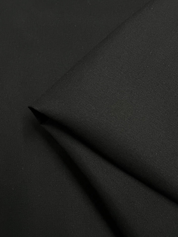 A close-up of Super Cheap Fabrics' Panama Suiting - Black (150cm), showcasing its smooth texture and clean lines.