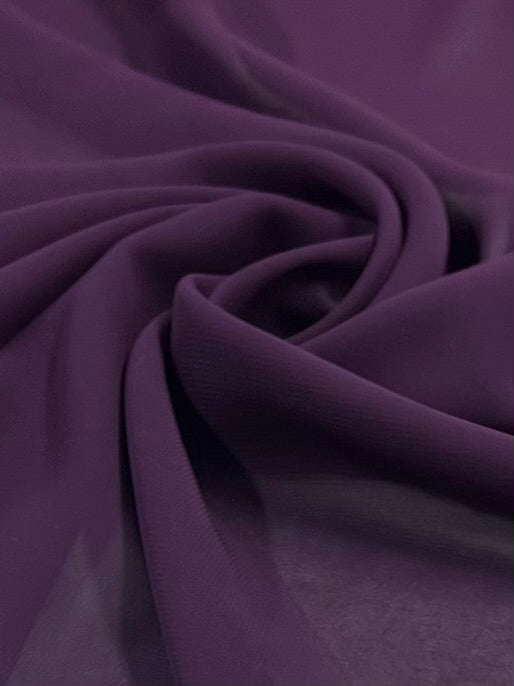 A close-up view of Super Cheap Fabrics' Hi-Multi Chiffon in Plum, 150cm wide, reveals smooth, flowing material with gentle folds and swirls. Its lightweight texture and delicate sheen enhance an ethereal charm.