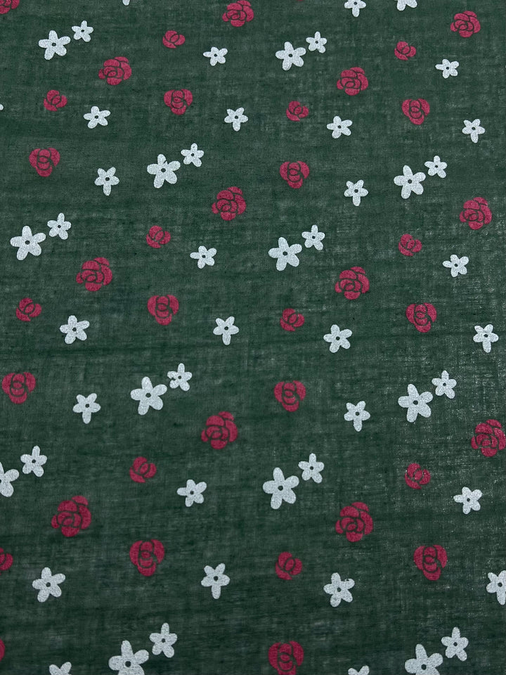 Super Cheap Fabrics' Linen Voile - Roses - 145cm is a lightweight fabric with a dark green background, featuring a breathable material adorned with small white flowers and red rose clusters.