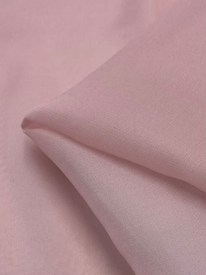 Close-up of Pure Silk Georgette - Pink Lotus - 135cm by Super Cheap Fabrics, showcasing its smooth texture and gentle pink hue.