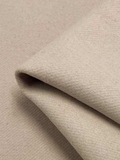 Close-up of folded Designer Wool in a tapioca color by Super Cheap Fabrics, showcasing its soft, textured surface. This heavy weight material is thick and cozy, ideal for garments or upholstery. .