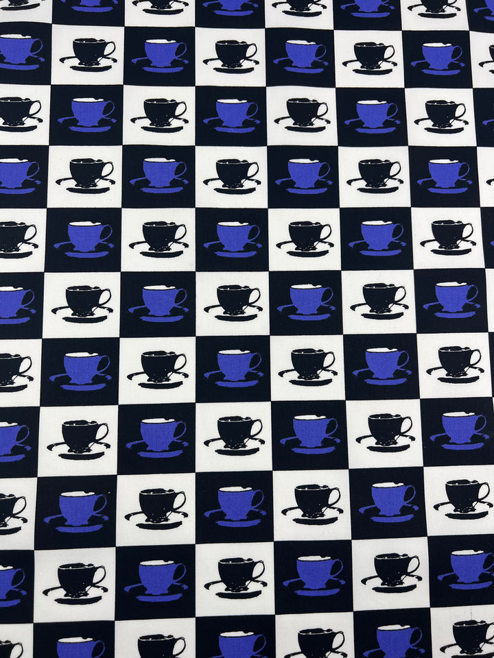 A repeating pattern featuring blue and black teacups and saucers against a black and white checkered background. The cups alternate in color and direction, creating a visually engaging, grid-like design on durable diagonal weave Cotton Drill - Purple MugKnight - 155cm fabric by Super Cheap Fabrics.