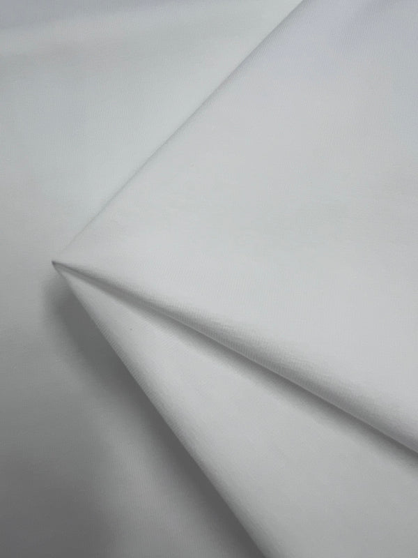 Close-up image of Super Cheap Fabrics' Cotton Lycra in Ivory, highlighting its texture and soft, smooth surface. This breathable fabric is neatly folded and arranged, emphasizing its clean and elegant appearance across 170cm.