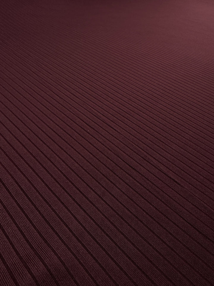 Close-up of Super Cheap Fabrics' Rib Knit in Burgundy (175cm) with parallel horizontal lines, creating a striped pattern. The lighting highlights the texture, offering a subtle sheen and hinting at maximum comfort.