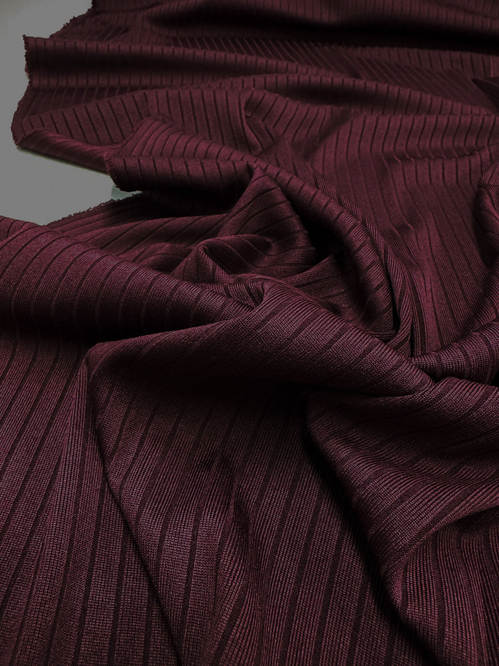 The Super Cheap Fabrics Rib Knit in Burgundy (175cm) is a luxurious, stretch textile with a rich hue and ribbed texture. Its draped folds and subtle sheen enhance its fine vertical lines, adding depth, dimension, and ensuring maximum comfort.