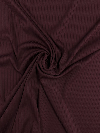 Super Cheap Fabrics' Rib Knit in Burgundy, measuring 175cm, features a subtle ribbed texture gathered into a swirl, creating soft folds and shadows for ultimate comfort.