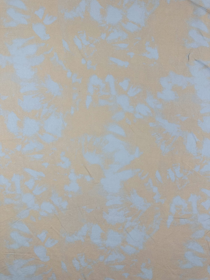 Super Cheap Fabrics' Linen Viscose - Blue Bell features a beige fabric with a light blue tie-dye pattern for an abstract, textured look. Ideal for crafting elegant dresses, this 140cm fabric offers comfort and style in limited stock.