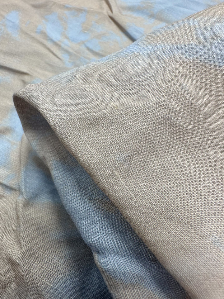 A close-up of Super Cheap Fabrics' "Linen Viscose - Blue Bell - 140cm" reveals a simple weave with light brown and blue tones. Slight creases create soft, flowing lines, perfect for fancy dresses. Limited stock available—grab yours before it's gone!.