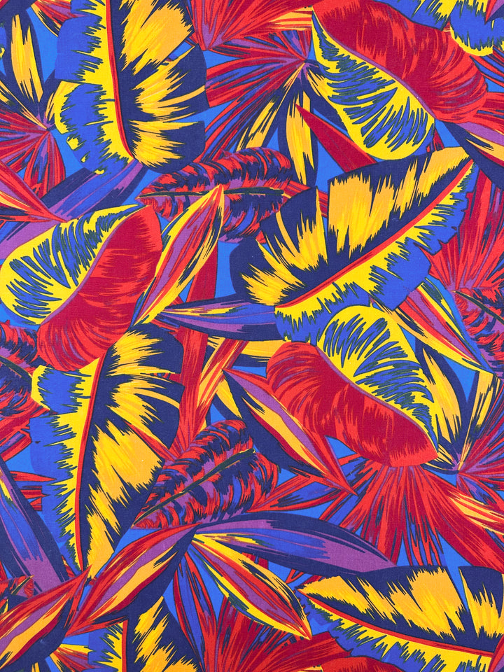 The Palm Scarlet fabric by Super Cheap Fabrics features vivid red, yellow, and blue feather-like patterns for dynamic, overlapping compositions. Its energetic colors add vibrancy to any home décor. Available in 140cm width cotton duck material.