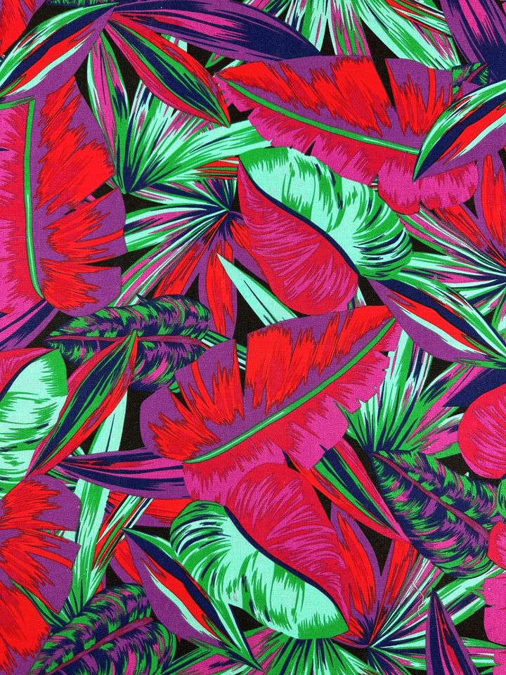 The Palm Cockatoo cotton duck fabric by Super Cheap Fabrics showcases a vibrant tropical pattern with overlapping leaves in bold shades of red, green, pink, and purple. It's perfect for adding a lively and colorful touch to your home décor. Width: 140cm.