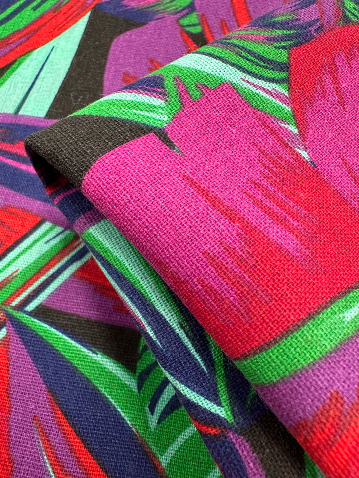 Close-up of Super Cheap Fabrics' Cotton Duck - Palm Cockatoo, 140cm wide. This medium-weight fabric features a vibrant abstract pattern in shades of pink, red, green, and purple with overlapping shapes and bold lines, perfect for adding a dynamic touch to your home décor.