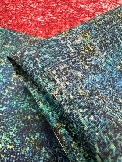 A close-up of the Linen Blend - Fields from Super Cheap Fabrics reveals a colorful, breathable fabric in green, blue, red, and gold. Intricately folded, its multi-dimensional design is perfect for versatile use. Width: 150cm.