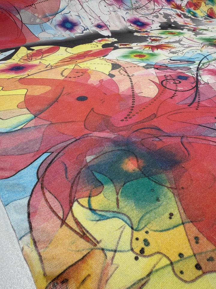 A close-up of Super Cheap Fabrics' Viscose Knit - Watercolour Bloom (142cm), featuring abstract, swirling patterns in bright red, yellow, pink, green, and blue with black dotted lines and floral designs.