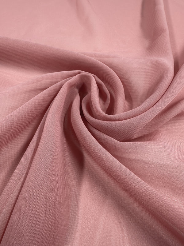 The Hi-Multi Chiffon in Brandied Apricot by Super Cheap Fabrics, 145cm wide, features a soft pink hue with a lightweight, smooth texture. Elegantly draped with subtle sheerness and gentle folds, it evokes a sense of movement and reflectivity akin to floaty tops.