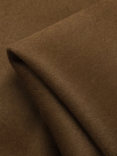 Close-up of folded brown Wool Cashmere - Emperador fabric from Super Cheap Fabrics, showcasing its luxurious softness and smooth matte finish. The gentle curve reveals this 150cm fabric's thickness and premium quality.