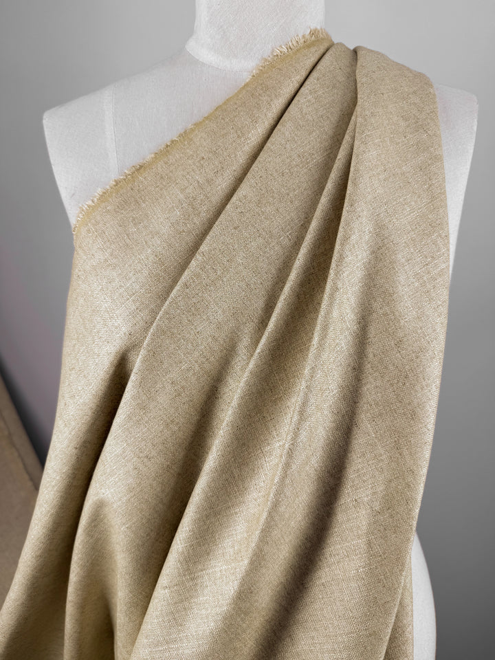 The Linen Viscose - Biscotti - 144cm by Super Cheap Fabrics elegantly drapes over the mannequin, showcasing its soft texture and subtle weave. Gentle folds form, highlighting its lightweight quality against a plain background, making it ideal for upholstery projects.