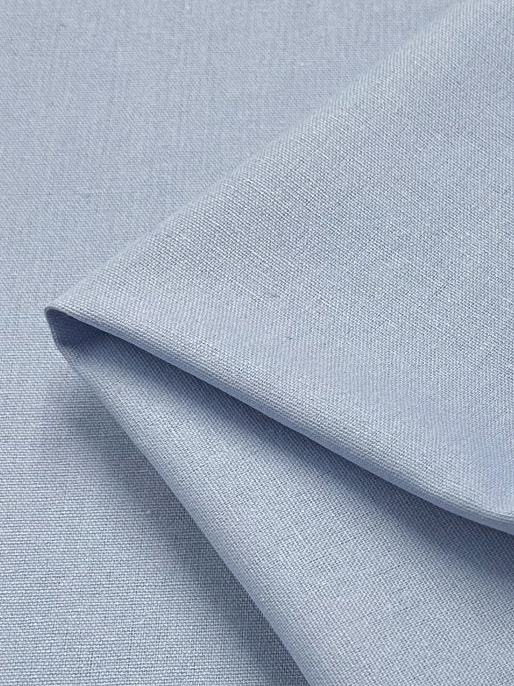 A close-up of a folded piece of Linen Blend - Skyway - 145cm from Super Cheap Fabrics. The texture of the Italian linen blend fabric is clearly visible, showcasing its fine weave. The light-medium weight linen appears smooth and neatly arranged.