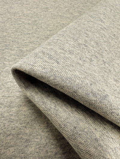 A close-up view of a folded piece of Super Cheap Fabrics' Unbrushed Fleece in Ancient Scroll. The high-quality material, measuring 163cm wide, has a soft, slightly textured surface with a subtle speckled pattern. The edges of the fold are clean and crisp, showcasing the fabric's ultra-soft flexibility and thickness.