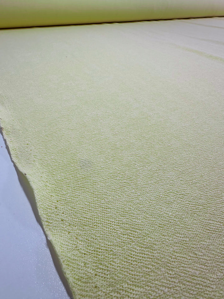 A close-up of a large roll of French Vanilla Unbrushed Fleece from Super Cheap Fabrics, measuring 160cm wide and spread out on a flat surface. The texture of the heavy-weight fabric reveals a subtle knit pattern.