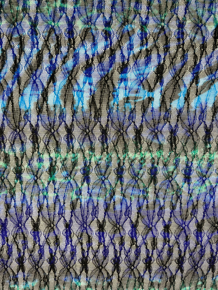 Abstract image featuring a close-up of Super Cheap Fabrics' Evening Lace - Avatar - 140cm. The material has a net-like grid design in black, with a background showcasing a gradient of blue, teal, and gray hues. The interplay of colors and texture gives the image a dynamic, almost three-dimensional effect.