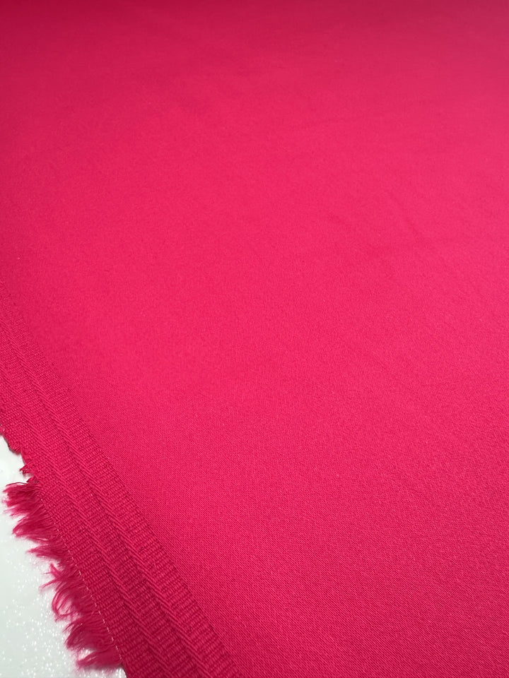 A close-up of Super Cheap Fabrics' "Plain Sateen - Rose Red - 140cm" shows the vibrant cotton fabric with a slightly textured surface and visible edge fringe, luxuriously laid flat.