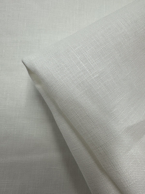 A close-up of Super Cheap Fabrics’ Pure Linen - Off White 01 (150cm) shows its breathable texture and smooth, linen-like surface, neatly folded at one corner against a matching background.