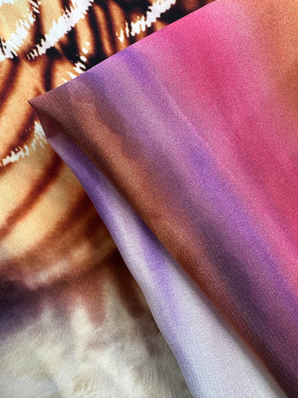 Close-up of two pieces of Super Cheap Fabrics' Pure Silk - Electric Bloom - 140cm, showcasing vibrant swirling orange and black patterns, plus a pink, purple, and brown gradient. The smooth texture makes this silk perfect for high-end fashion.