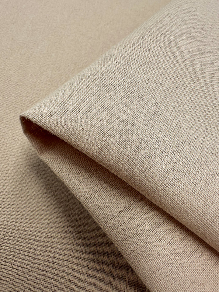 A close-up of Super Cheap Fabrics' Ramie Linen in Hazelnut, measuring 150cm, showcases the intricate weave and texture of the light brown natural fiber. The fabric is neatly folded.