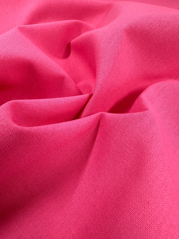 A close-up of the Ramie Linen in Azalea Pink by Super Cheap Fabrics reveals its crumpled texture with a soft feel and slight sheen, crafted from natural fibers, forming gentle folds and shadows.