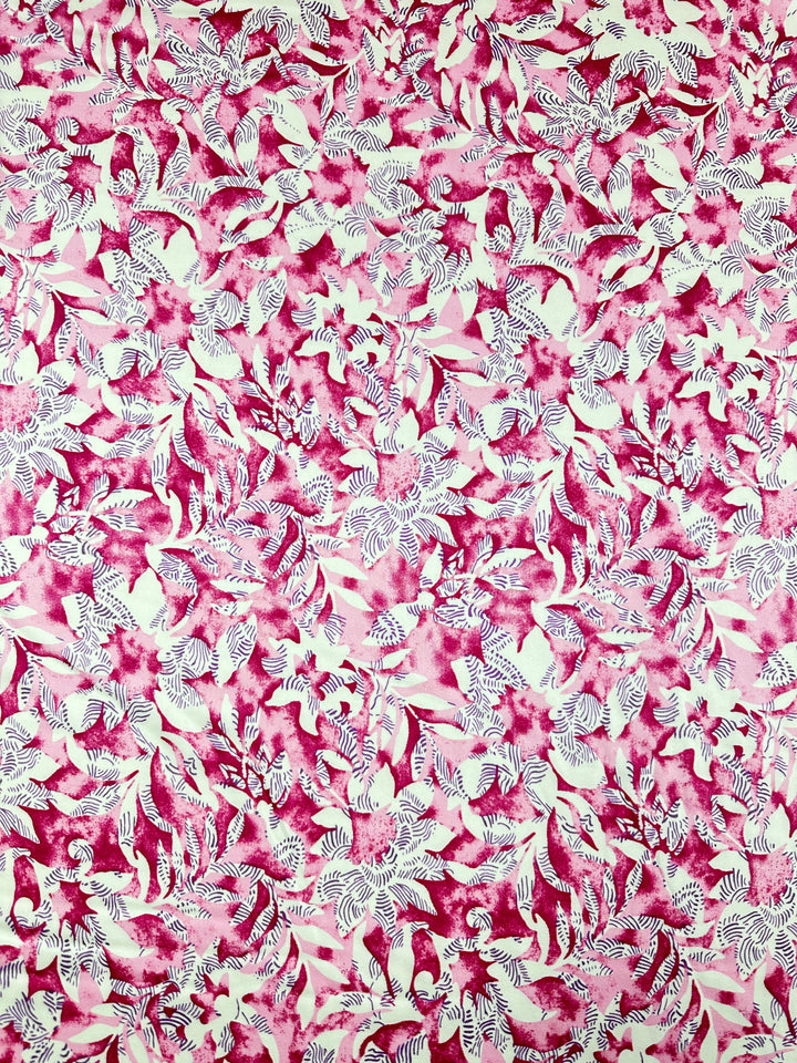 The Silky Satin - Lotus from Super Cheap Fabrics features a lively pattern of pink and white leaves and floral designs, creating an elegant texture on the lightweight satin, emulating the beauty of exquisite printed satins.