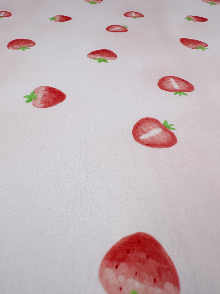 The Tutti Fruity Printed Cotton from Super Cheap Fabrics is a lightweight material that showcases a delightful design of red strawberries dotted on a white background. Each strawberry is accented with tiny green leaves, bringing an element of charm to this natural cotton fabric. The fabric measures 150cm in width.