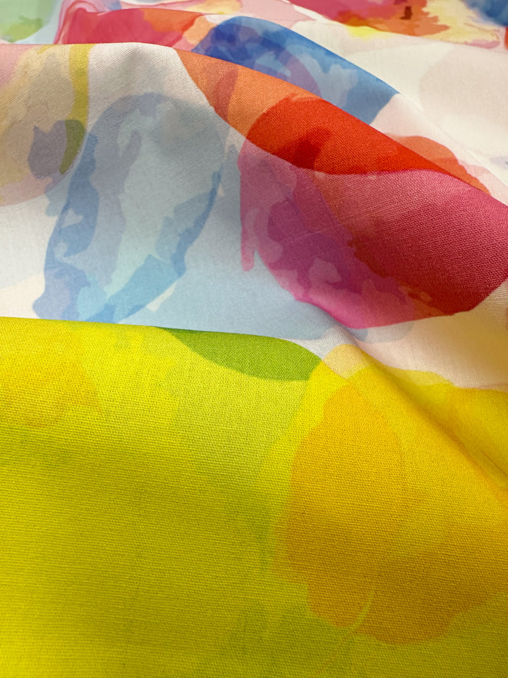 A close-up view of the vibrant Printed Cotton - Bubble - 150cm from Super Cheap Fabrics showcases an abstract pattern with flowing shapes in bold colors such as yellow, blue, red, and green. This dynamic design is perfect for clothing and household items, offering comfort and style with its natural cotton fibers.