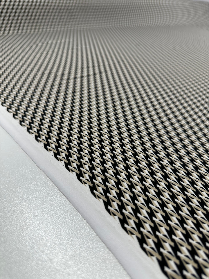 Close-up of a textured surface on medium-weight fabric, "Link Up" by Super Cheap Fabrics, featuring a repeating pattern of small, raised diamond shapes. The pattern appears on an angled plane, creating depth and perspective. This 150cm gray printed Lycra displays highlights and shadows that give it a three-dimensional look.