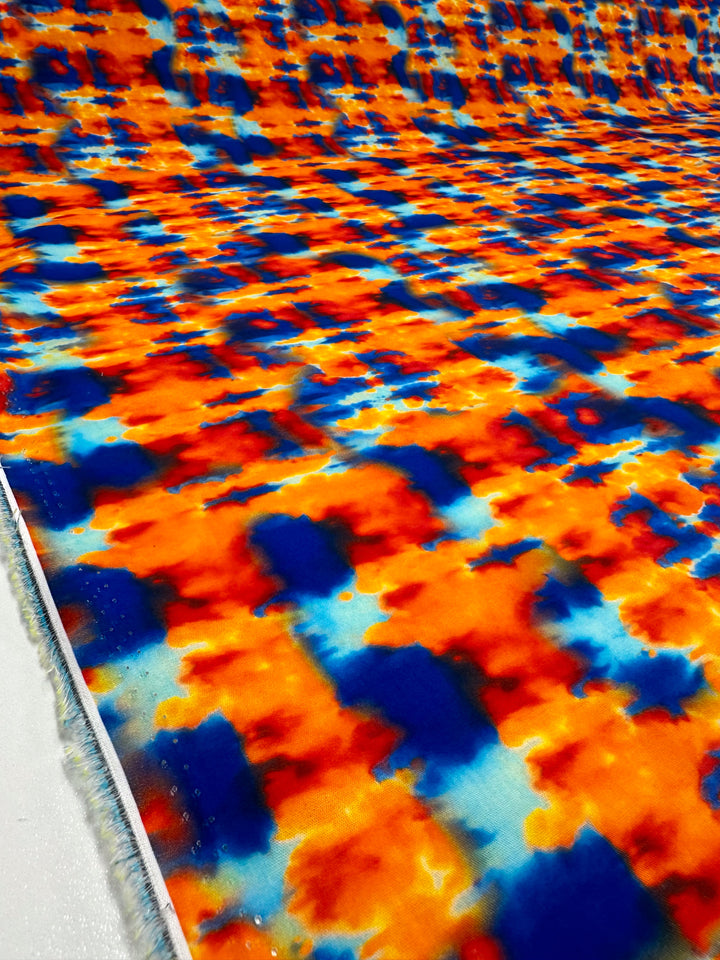 The Printed Cotton - Rosch - 150cm from Super Cheap Fabrics showcases a striking abstract pattern in bold orange, blue, and white tones that creates a visually dynamic and colorful surface. Made from natural cotton fibers, the design repeats across the fabric to add movement and texture, making it ideal for home decor projects.