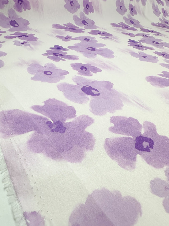 The "Printed Cotton - Bellflower - 150cm" from Super Cheap Fabrics features a gentle pattern of soft purple flowers against a white backdrop. The loosely painted blooms offer a watercolor effect, beautifully emphasizing the charm of natural cotton fibers. This fabric is ideal for crafting both clothing and household items with its elegant repeating floral design.