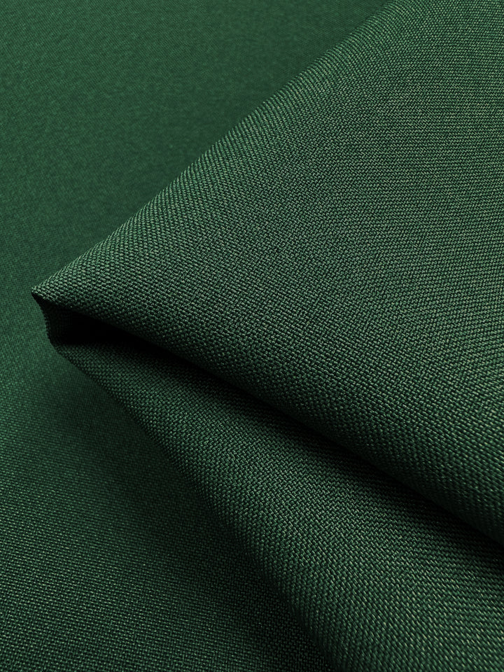 Close-up of Super Cheap Fabrics' Panama Suiting in Bottle, a 150cm medium-weight, dark green polyester with a textured weave. This fabric has a subtle sheen and smooth appearance, showcasing intricate detailing—perfect for uniforms.