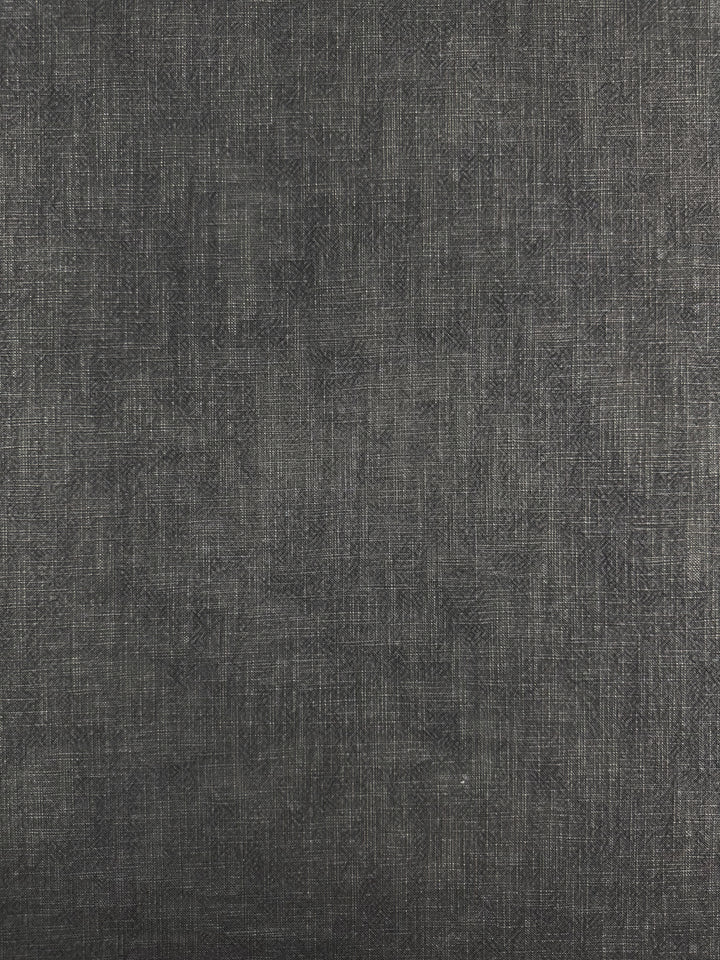 A close-up of the Basket Dyed Cotton fabric by Super Cheap Fabrics in charcoal reveals a subtle twill weave pattern. The fine interwoven threads create a soft, matte finish, suggesting it is 100% cotton upholstery fabric suitable for both clothing and interior design. With its 140cm width, this textured dark gray surface presents versatility for various applications.