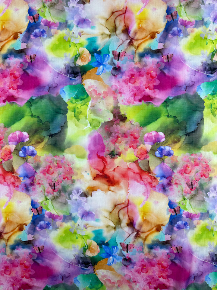 Discover the Designer Cotton - Alice - 150cm by Super Cheap Fabrics, showcasing a vibrant watercolor pattern with an array of colorful flowers and leaves in stunning shades of pink, purple, green, yellow, and blue. This abstract and symmetrically repeated design on lightweight cotton fabric offers a harmonious and lively floral composition, ideal for luxury sewing projects.