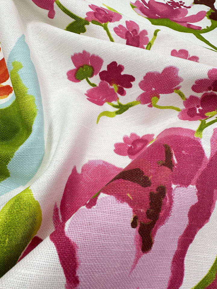 Close-up of the Blended Duck - Tambala fabric by Super Cheap Fabrics, showcasing a medium weight duck material with a floral pattern. It features pink blossoms and green leaves on a white background. This linen cotton blend has a textured appearance, with vibrant colors enhancing the design—perfect for home décor accessories.