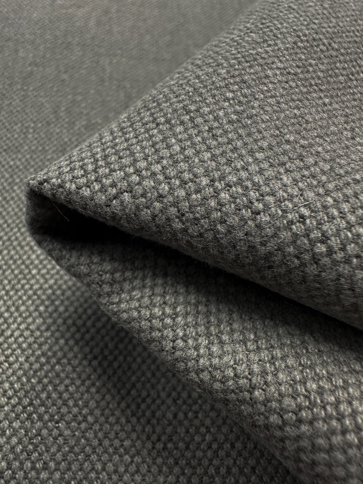 A close-up of folded Canvas Linen Denim in Brushed Nickel from Super Cheap Fabrics reveals a textured waffle weave pattern. The fabric looks soft and thick, highlighting its intricate texture and subtle shading, making it ideal for sophisticated home décor.