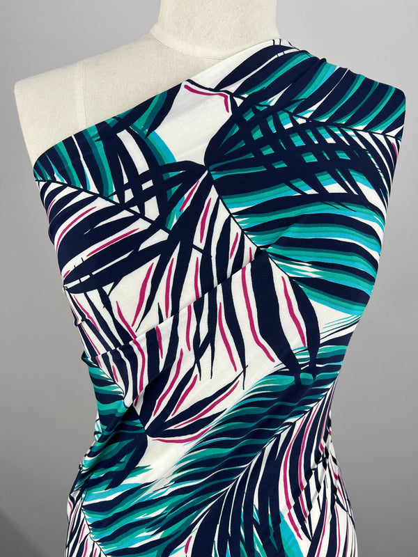 A close-up view of a one-shoulder dress on a mannequin, showcasing the vibrant Palma print in shades of green, blue, and white from Super Cheap Fabrics' Printed Lycra collection, with accents of pink and navy. Made from medium-weight Polyester/Spandex fabric measuring 150cm wide, the dress features a ruched bodice for a stylish and textured look.