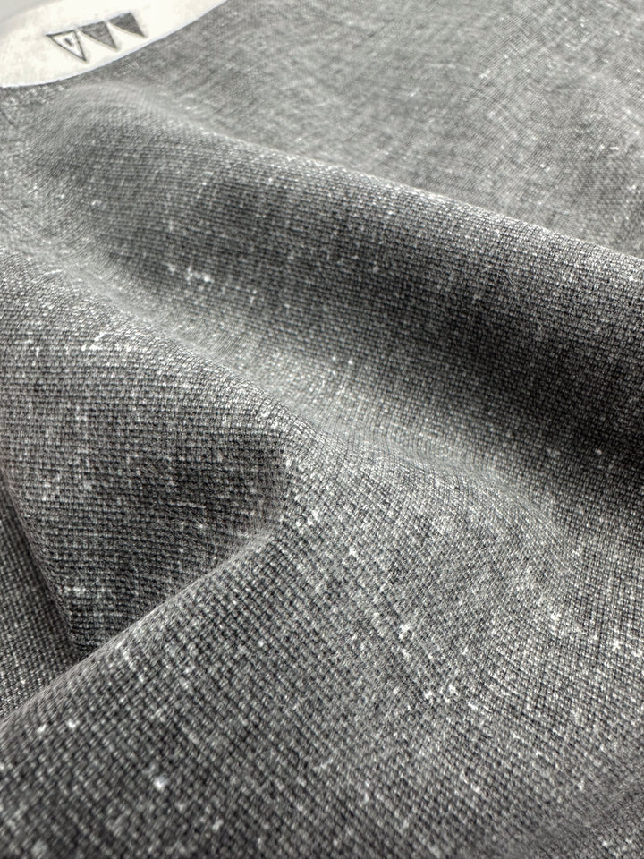 Close-up of Super Cheap Fabrics' Upholstery Canvas - Silver - 140cm, a heavyweight cotton with fine weave and soft, mottled texture. The gently folded fabric creates shadows and highlights, ideal for a cozy yet elegant upholstery finish.