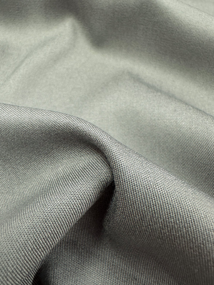 Close-up of the Chambray - Flint Grey - 150cm fabric by Super Cheap Fabrics, featuring its lightweight texture with a slight sheen. Draped in soft folds, it showcases its delicate texture and subtle shine.