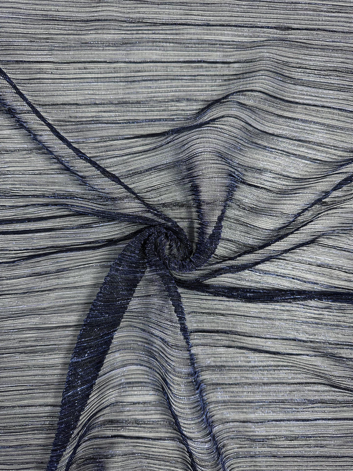 Close-up of crumpled, textured lightweight fabric with a spiral design in cobalt and dark navy. The Metallix Pleat from Super Cheap Fabrics has a smooth polyester material with fine horizontal stripes that catch the light, giving it a slightly shiny appearance.