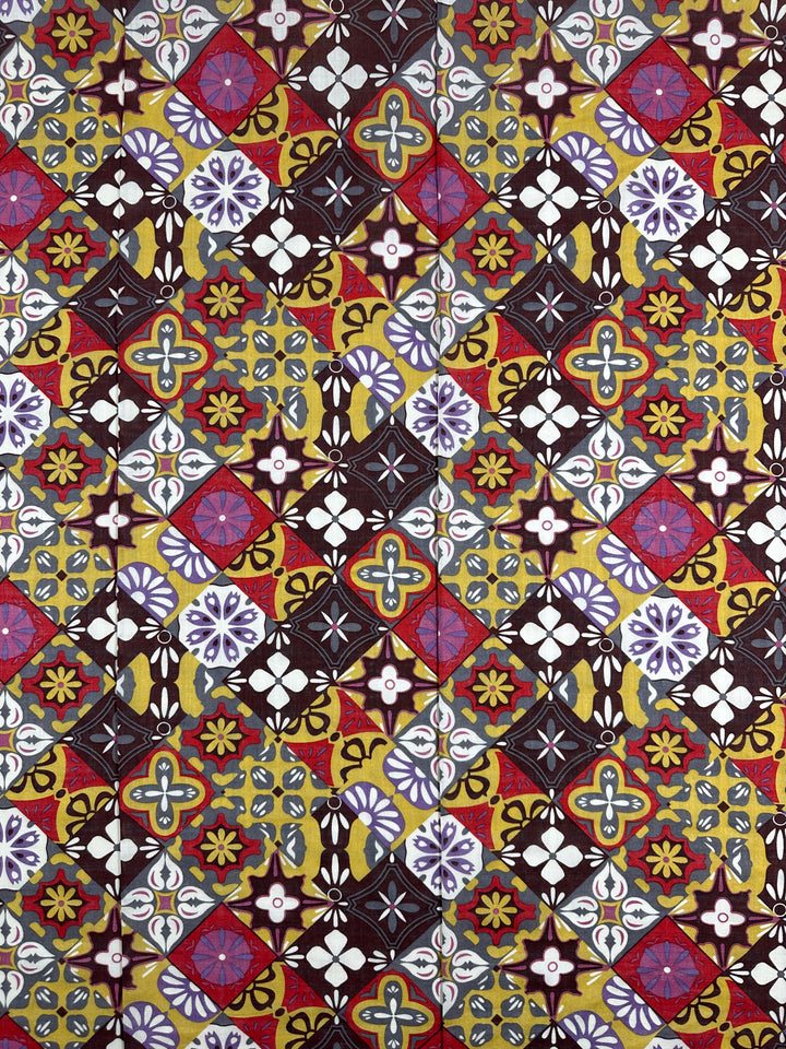 Introducing the "Linen Blend - Mosaic - 145cm" from Super Cheap Fabrics—a lightweight linen fabric showcasing a lively geometric pattern. This intricate design features a harmonious blend of diamonds, circles, and floral motifs in striking red, yellow, black, and purple hues. The breathable fabric artfully constructs a complex and symmetrical mosaic on its surface.