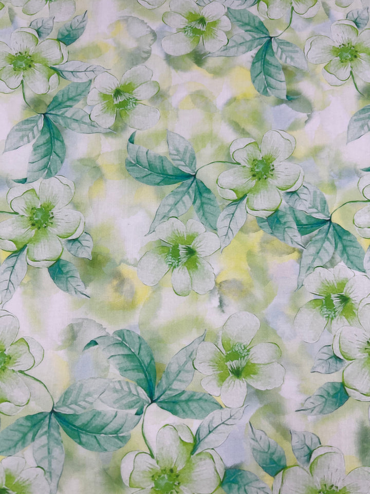 Introducing the Designer Cotton - Periwinkle - 150cm by Super Cheap Fabrics. This exquisite cotton fabric features a beautiful floral pattern showcasing green and white flowers and leaves. The design is highlighted by pale green centers and petals, surrounded by lush greenery, all set against a delicate blend of yellow and green hues that creates a stunning watercolor effect. Ideal for luxury sewing projects.