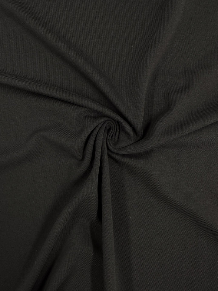 A close-up of Super Cheap Fabrics' Cotton Lycra - Black, measuring 190cm, shows a twisted pattern with a spiral effect. The fabric is smooth and slightly matte, ideal for bodycon dresses because of its breathable nature.