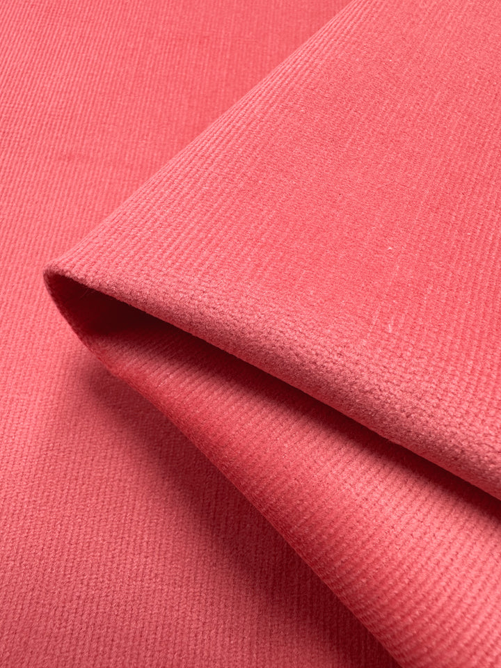 Close-up of two layered pieces of Micro Wale Corduroy - Dubarry, 137cm by Super Cheap Fabrics, showcasing a pink ribbed texture that adds depth and interest, reminiscent of winter clothing.